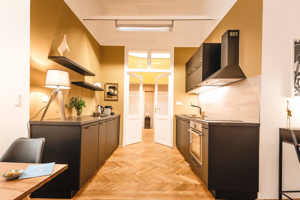 A modern kitchen with a herringbone floor, built-in appliances, and a pendant light.