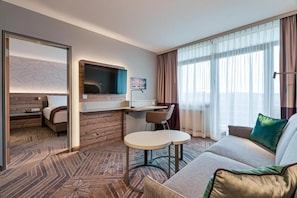 Una habitación de hotel con cama, escritorio con silla, sofá y televisor.