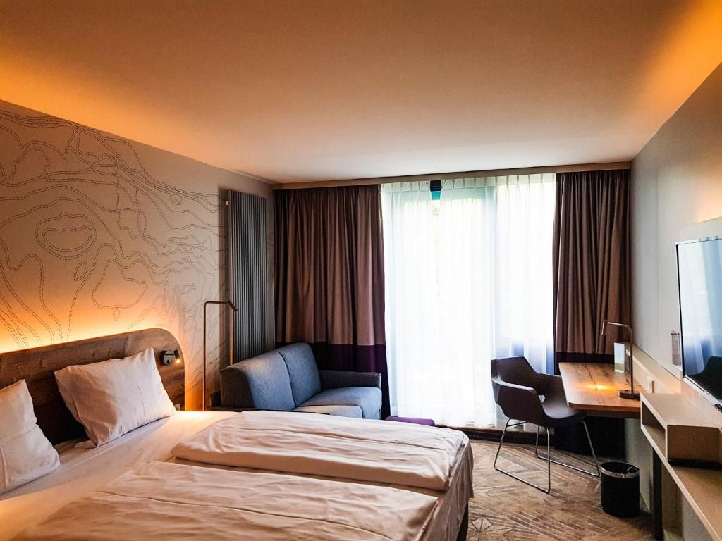 Una habitación de hotel con cama, escritorio y silla.