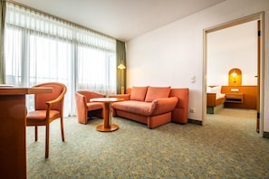 A hotel room with a sofa, a chair, a small table, and a bed with a nightstand. - feelMOOR Das Gesundresort Bad Wurzach (Bad Wurzach)