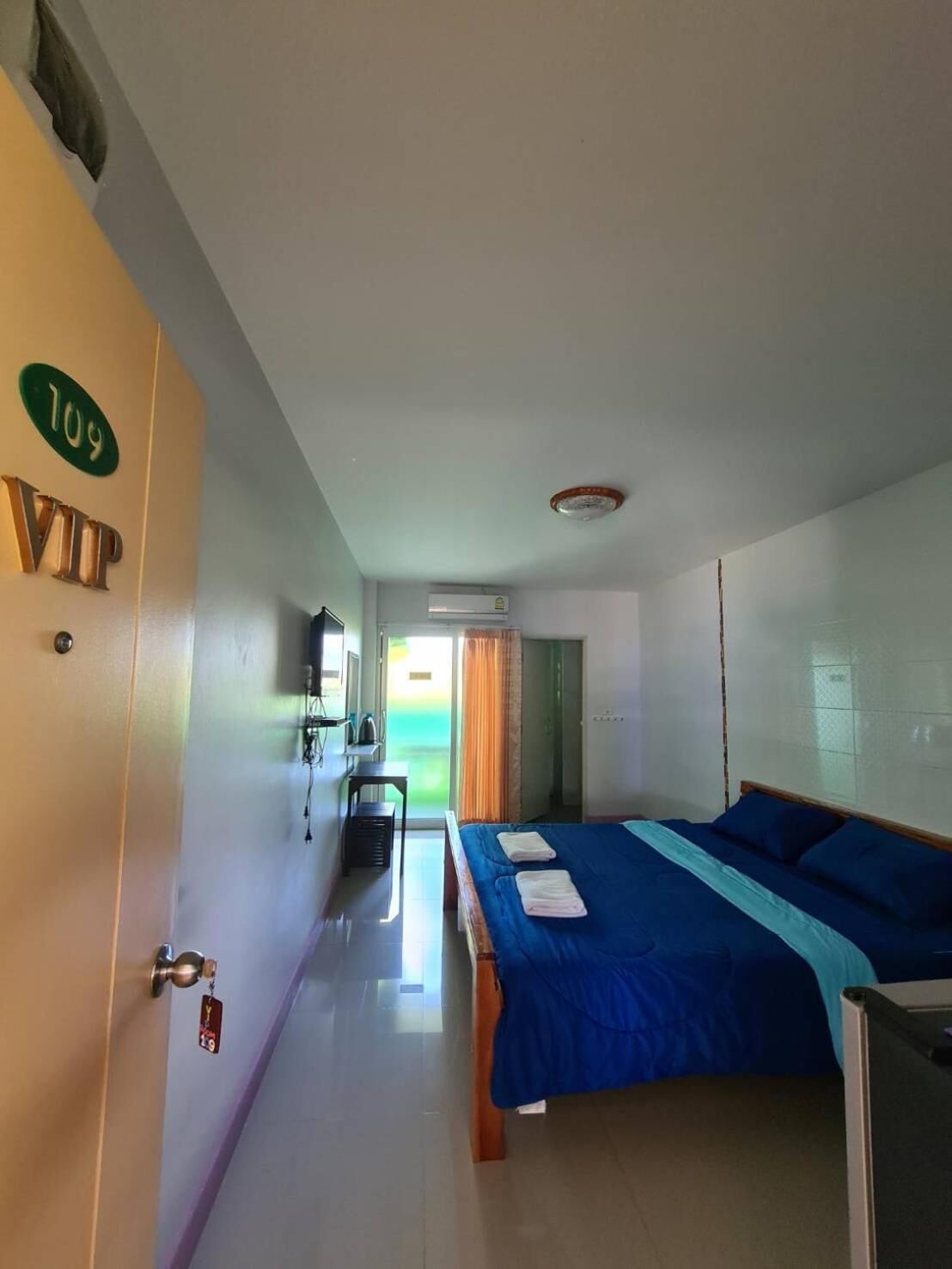 Habitación de hotel con cama, escritorio, unidad de aire acondicionado y una puerta con la indicación '109 VIP'.