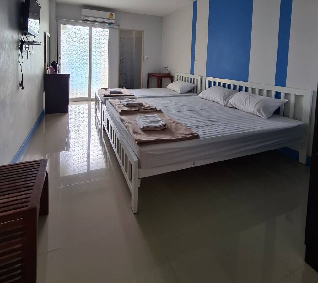 Un dormitorio con una cama grande, una mesita de noche pequeña, un armario y una ventana con vista a una pared estampada.