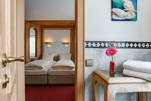 Habitación de hotel con cama doble, baño pequeño con espejo y un cuadro en la pared.