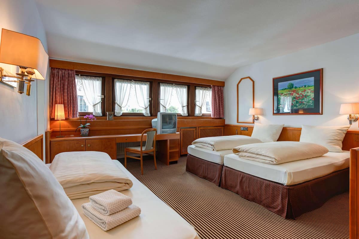Habitación de hotel con cama, escritorio, silla, televisor y un cuadro en la pared.