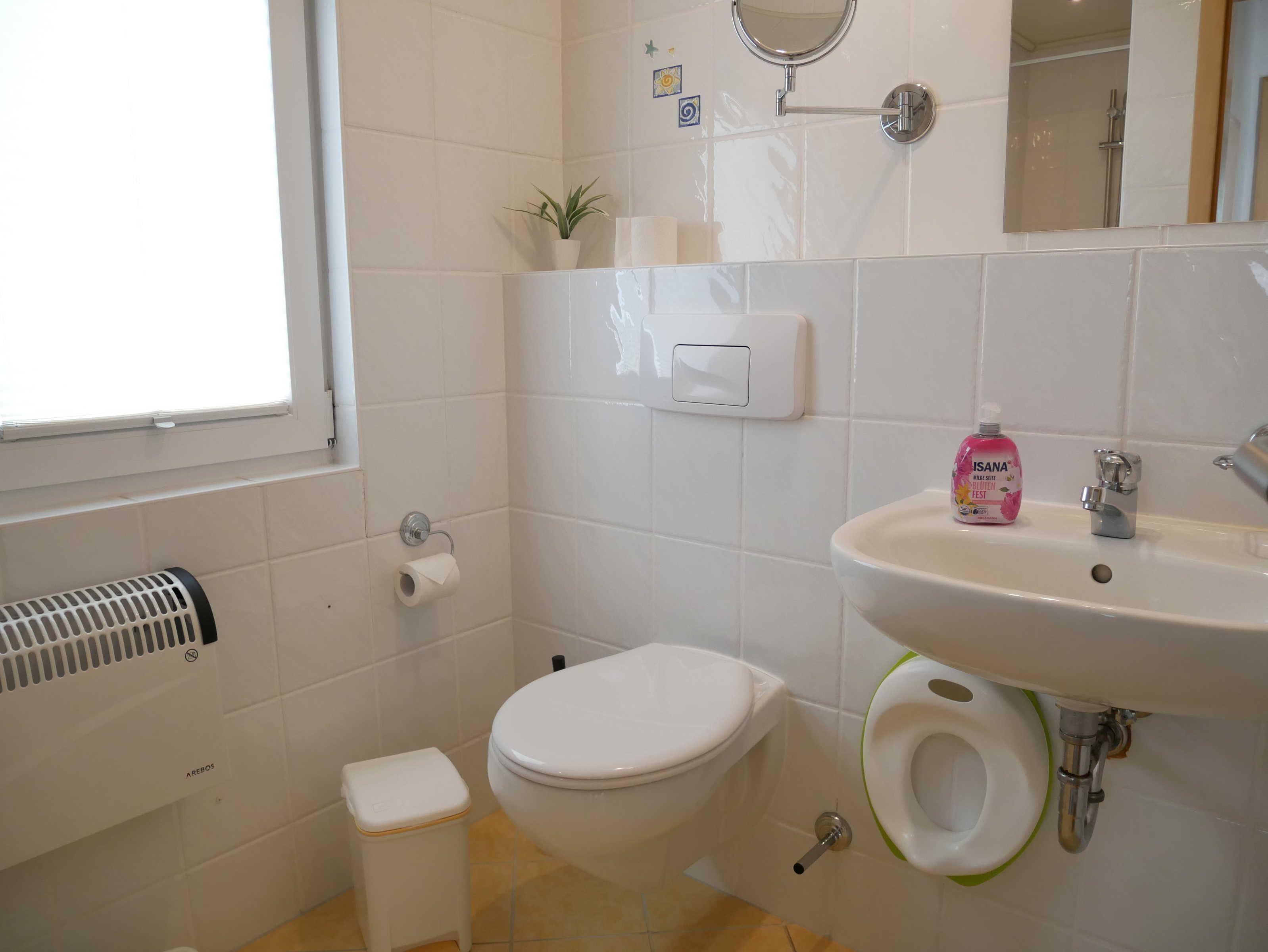 Un baño con inodoro, bidé, lavamanos y una ventana pequeña.