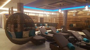 A modern lounge area with hanging chairs, sofas, and a large decorative sphere. - Molaris Lodge (Rio di Pusteria)