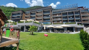 A modern multi-story hotel with outdoor seating and a grassy courtyard. - Molaris Lodge (Rio di Pusteria)