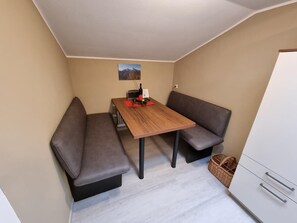 A small, cozy room with a wooden table, two grey sofas, and a white cabinet. - Ferienwohnung Grünstein, 2 bis 4 Personen, 60 qm, 1 separates Schlafzimmer, Balkon (Schönau am Königssee)