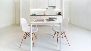 A modern kitchen with white cabinets, a white countertop, and two white chairs with wooden legs. - Casa Italia (Verona)