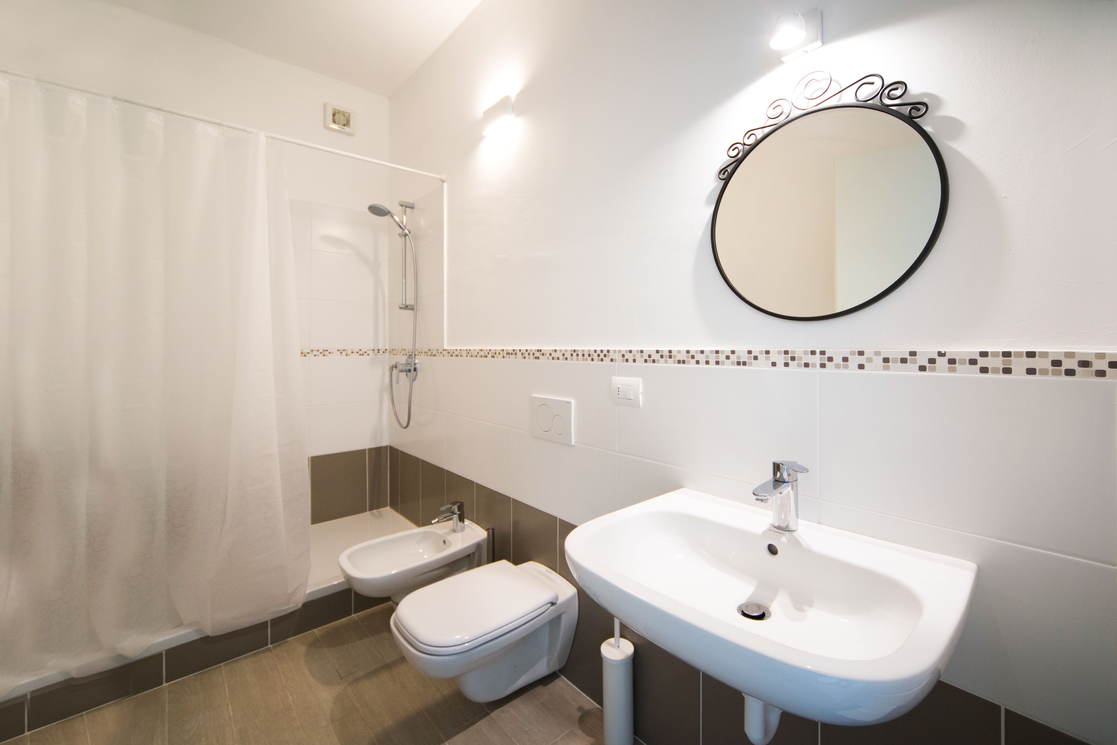 Een moderne badkamer met een douche, toilet, wastafel en een bidet.