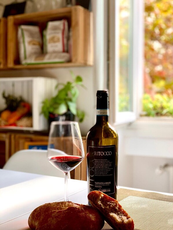 Una botella de vino Valpolicella Ripasso, una copa de vino tinto y un trozo de pan sobre una mesa.