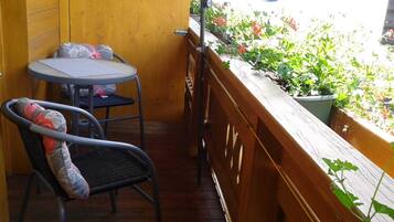 Een balkon met een houten hekwerk, een tafeltje en een stoel.