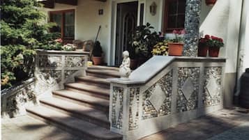 Un escalier en pierre menant à une porte, qui est entouré de plantes en pot et d’une statue.