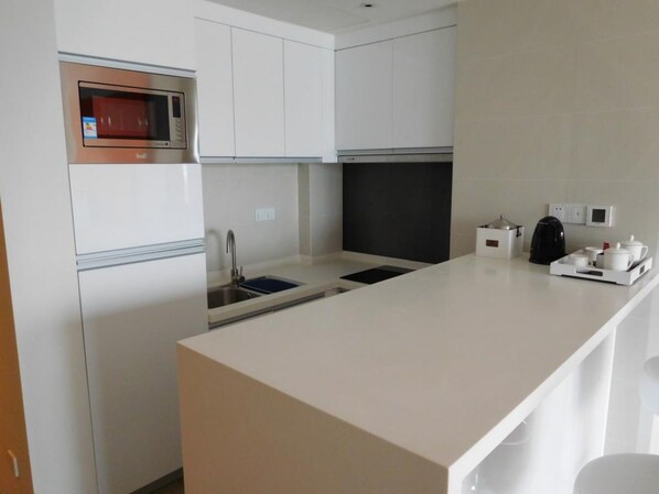 A modern kitchen with white cabinetry, a built-in oven, a sink, and a coffee station. - Dahengqin Superior Talent Hotel (Hengqin Port Branch) (Zhuhai)