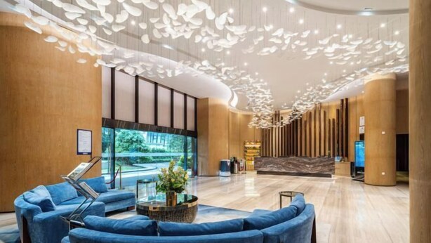 A modern lobby with blue sofas, a large aquarium, and a unique ceiling design. - Dahengqin Superior Talent Hotel (Hengqin Port Branch) (Zhuhai)