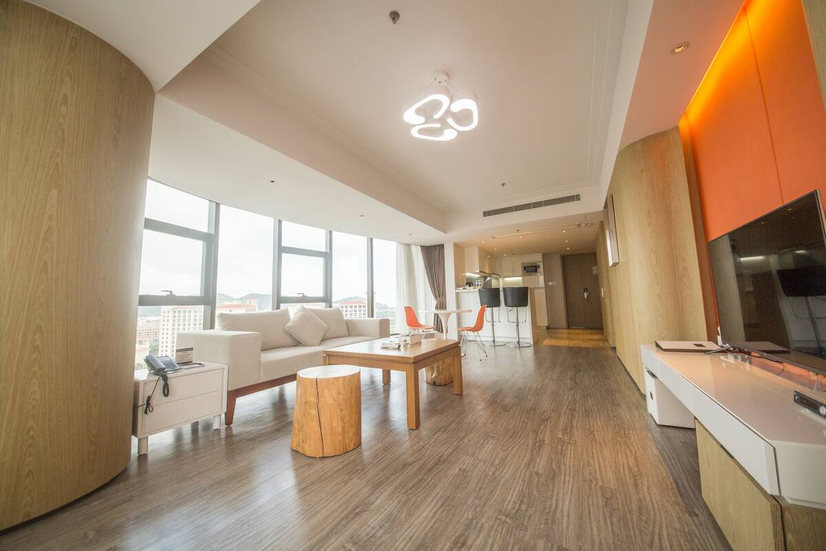 Ein großzügiger Wohnbereich mit großem Fenster, einem Holztisch, einer Couch und einer Küche mit modernem Design.