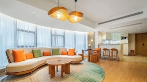 A modern living room with a curved sofa, round wooden coffee table, and pendant lighting. - Dahengqin Superior Talent Hotel (Hengqin Port Branch) (Zhuhai)