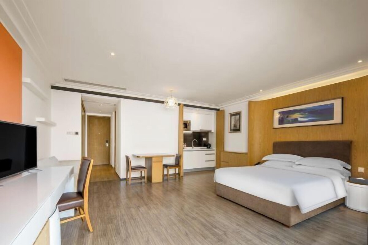 Habitación de hotel con cama, escritorio, silla, televisión y un cuadro en la pared.