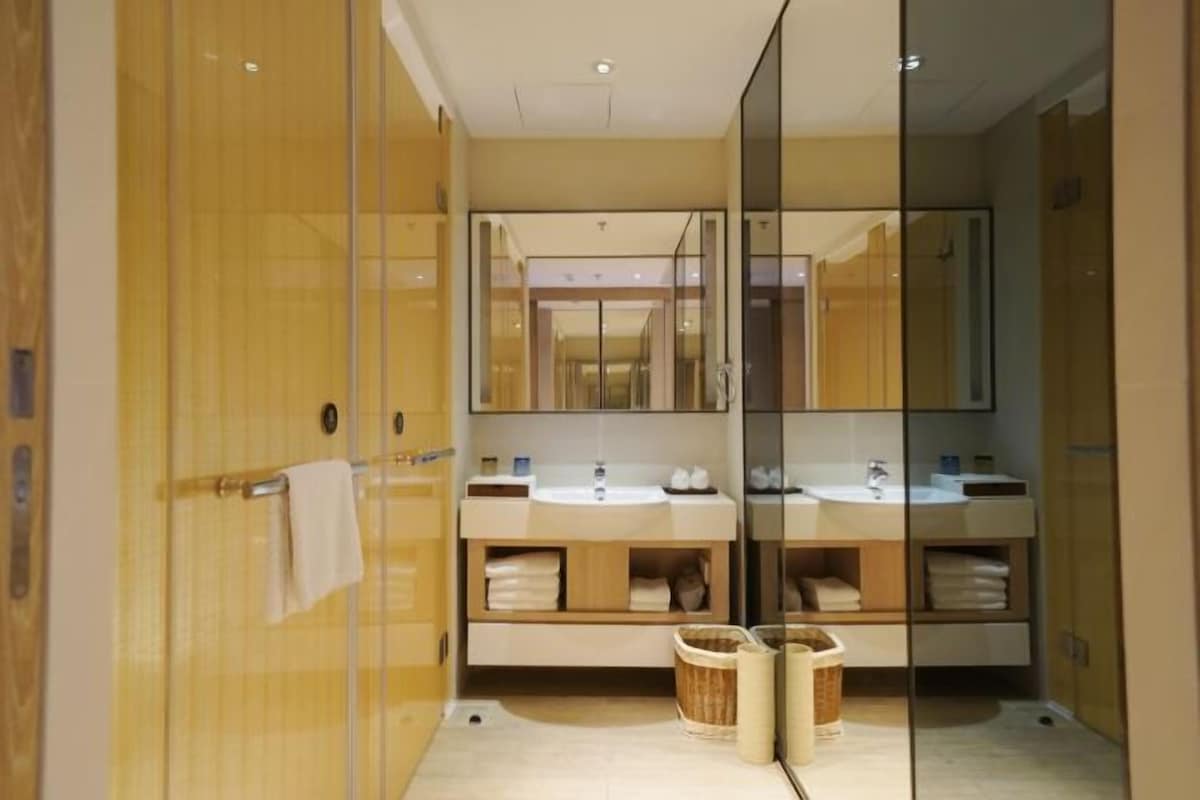 A modern bathroom with two sinks, a large mirror, and a glass shower enclosure.