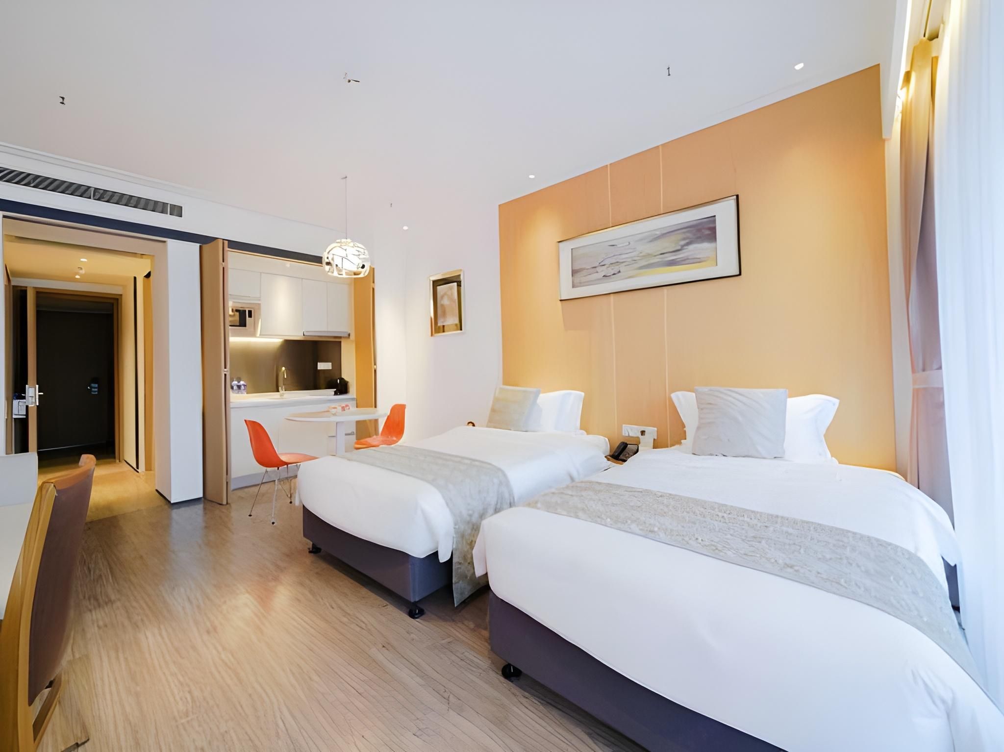 A hotel room with two beds, a desk, and a chair.