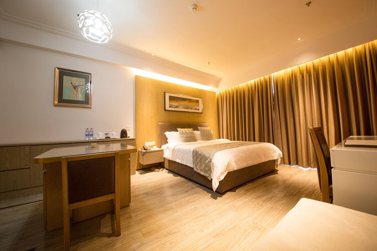 Ein Hotelzimmer mit Bett, Nachttisch, Schreibtisch und Lampe.