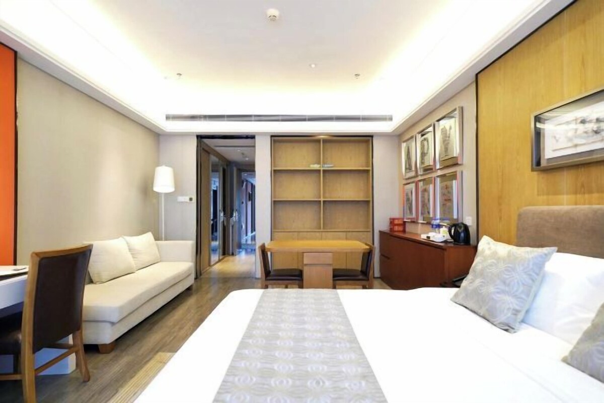Una habitación de hotel con cama, escritorio, sofá y estantería.