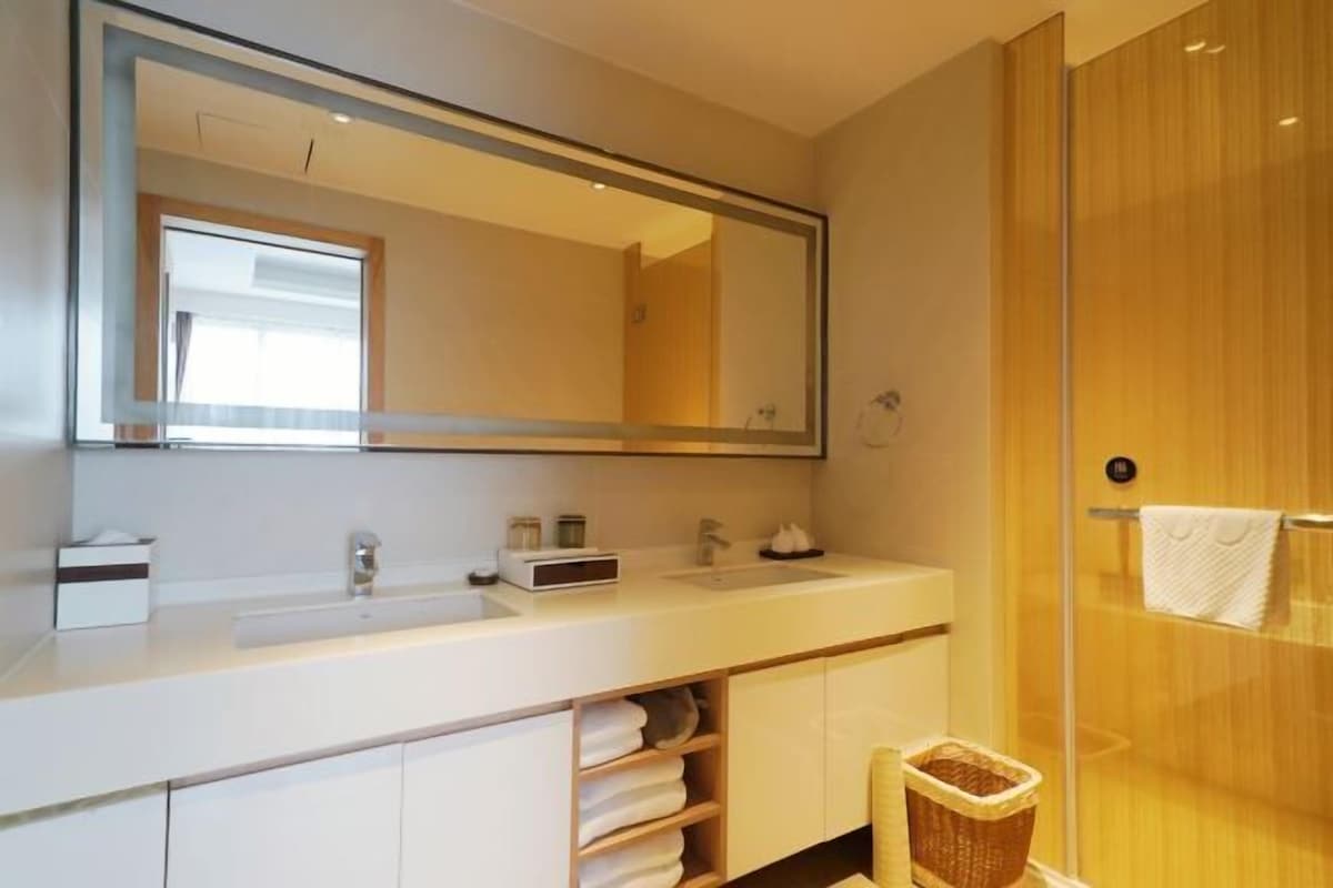 A modern bathroom with a large mirror, a sink, and a shower area.