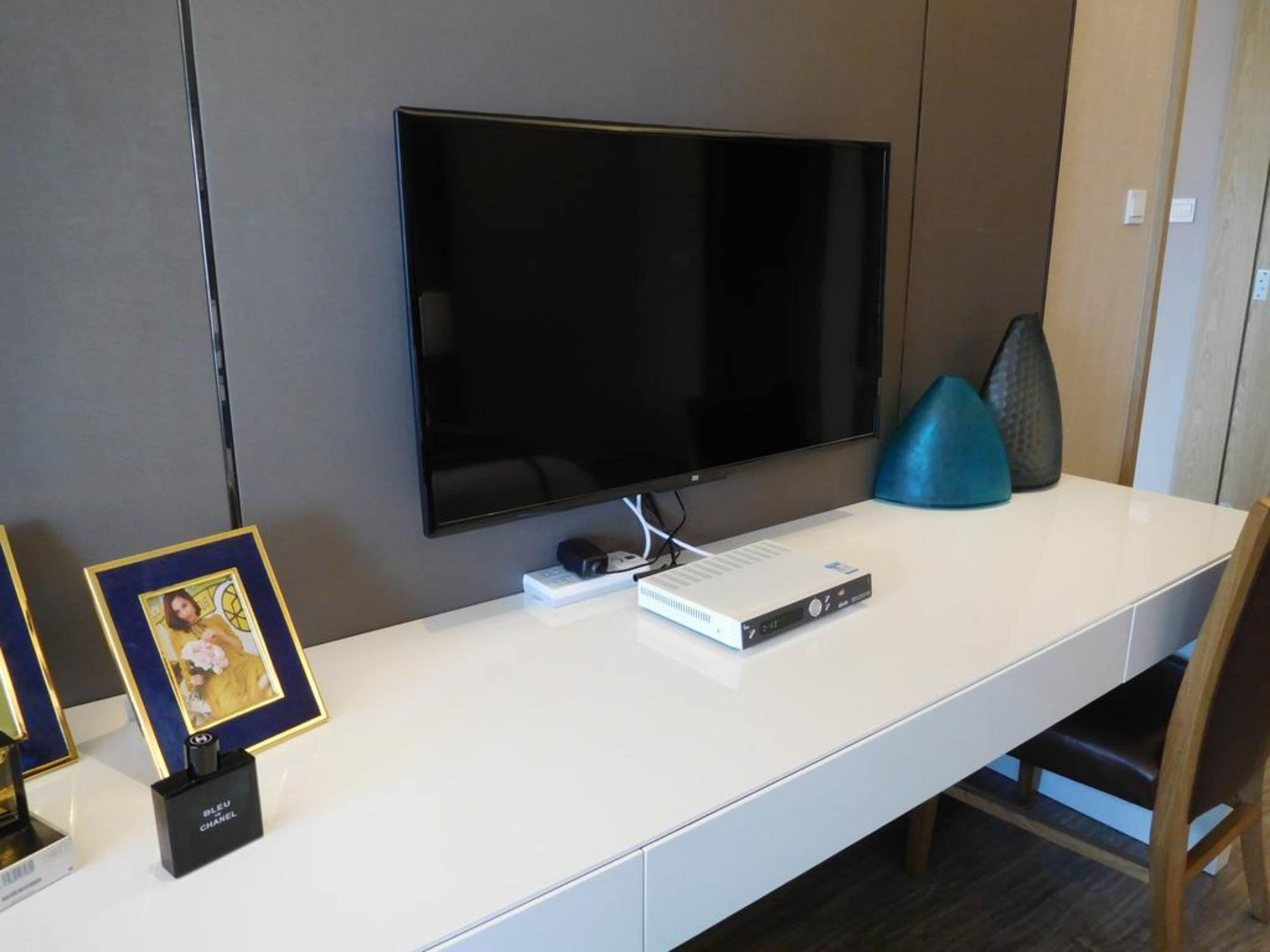 Una taula blanca amb un televisor de pantalla plana, una consola de jocs i una fotografia emmarcada.