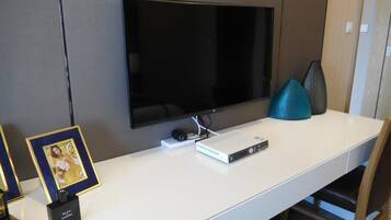 Una taula blanca amb un televisor de pantalla plana, una consola de jocs i una fotografia emmarcada.