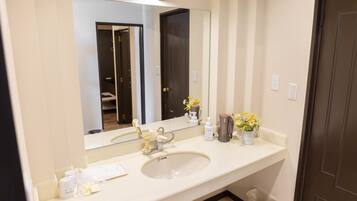 Un baño con un espejo grande, un lavabo y un cubo de basura.