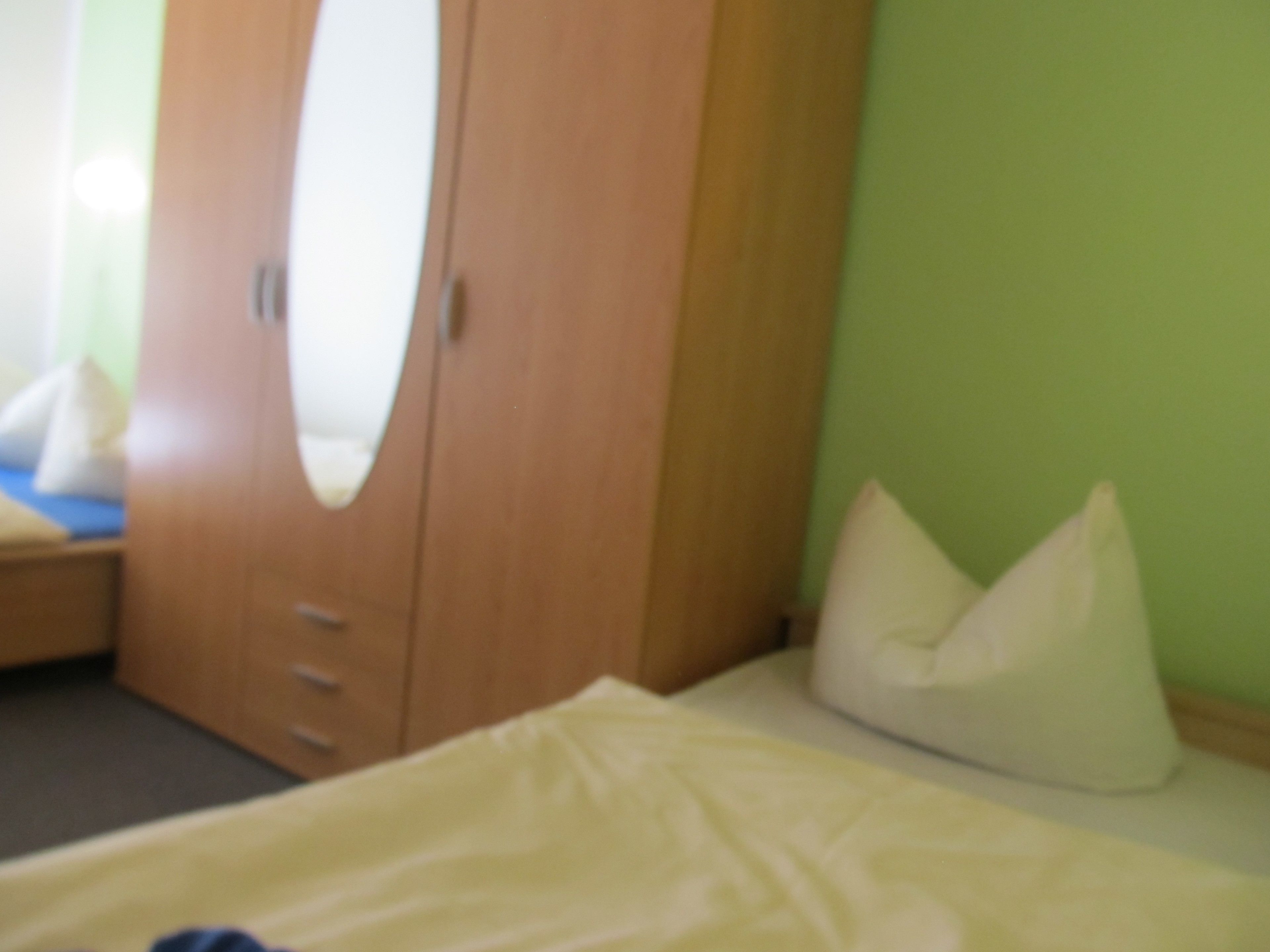 Een slaapkamer met een bed, een houten garderobe en een groene wand.