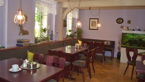 Un restaurant avec des tables et des chaises en bois, un grand aquarium et des lampes suspendues.