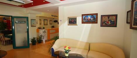 A reception area with a sofa, a glass table with flowers, and framed artwork on the wall.