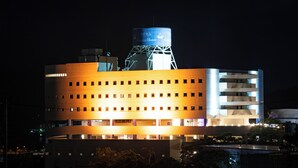 A hotel with a modern design, featuring a prominent water tower and multiple floors with evenly spaced windows. - Rycom Crystal Hotel (Okinawa)