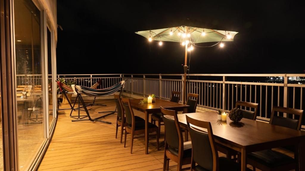 Een terras buiten met een eettafel, stoelen, een hangmat en een parasol.