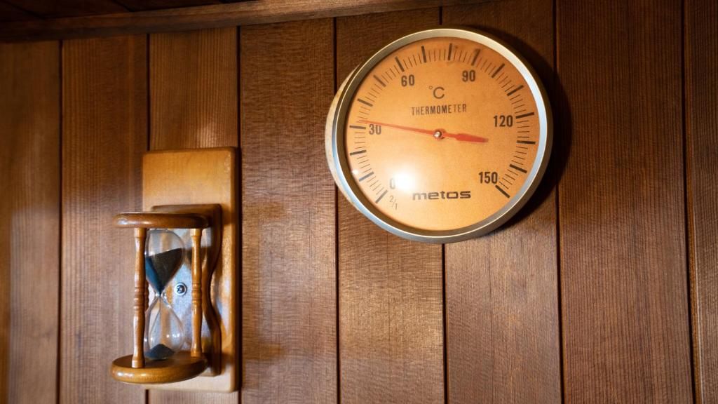 A wooden wall with a thermostat and a wall clock.