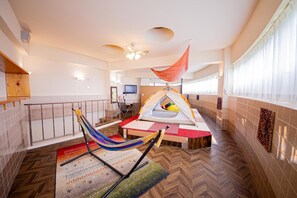 A hotel room with a hammock, a tent, a television, and a view of the outside. - Rycom Crystal Hotel (Okinawa)