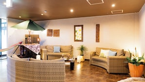 A cozy lounge area with wicker furniture, a small table, and a hammock. - Rycom Crystal Hotel (Okinawa)