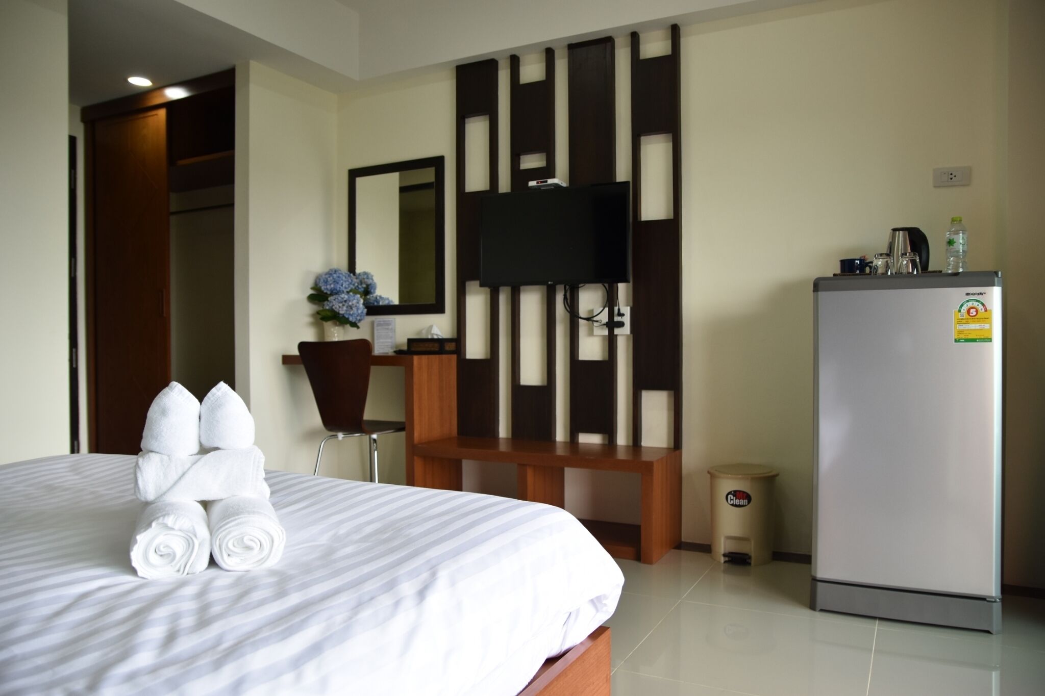 A hotel room with a bed, a television, a desk, and a refrigerator.