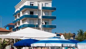 A multi-story hotel with balconies, white and blue exterior, and a clear blue sky. - Hotel Sayonara (Senigallia)