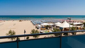 A beach with rows of umbrellas and sun loungers, a clear blue sky, and a calm sea. - Hotel Sayonara (Senigallia)