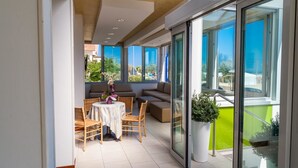 A modern interior with a dining area, seating, and a large sliding glass door leading to an outdoor space. - Hotel Sayonara (Senigallia)