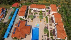 An aerial view of a residential area with multiple buildings, a swimming pool, and a covered parking area. - Amari Hotel (Polygyros)