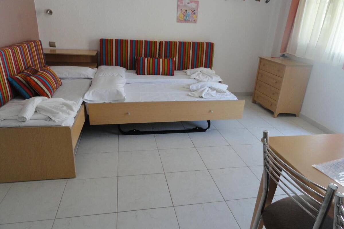 A bedroom with a bed, a chair, a small table, and a dresser.