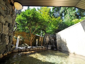 A clear outdoor pool area with a stone wall, a bamboo fence, and trees in the background. - Hotel Itamuro (Nasushiobara)