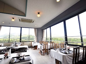 Enjoy meals in this stylish dining area with a high ceiling, large windows, and scenic views of the surrounding hills.