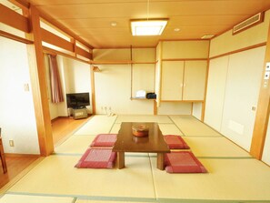 Traditional Japanese-style room with tatami flooring, featuring a low table, cushions, and sliding doors.
