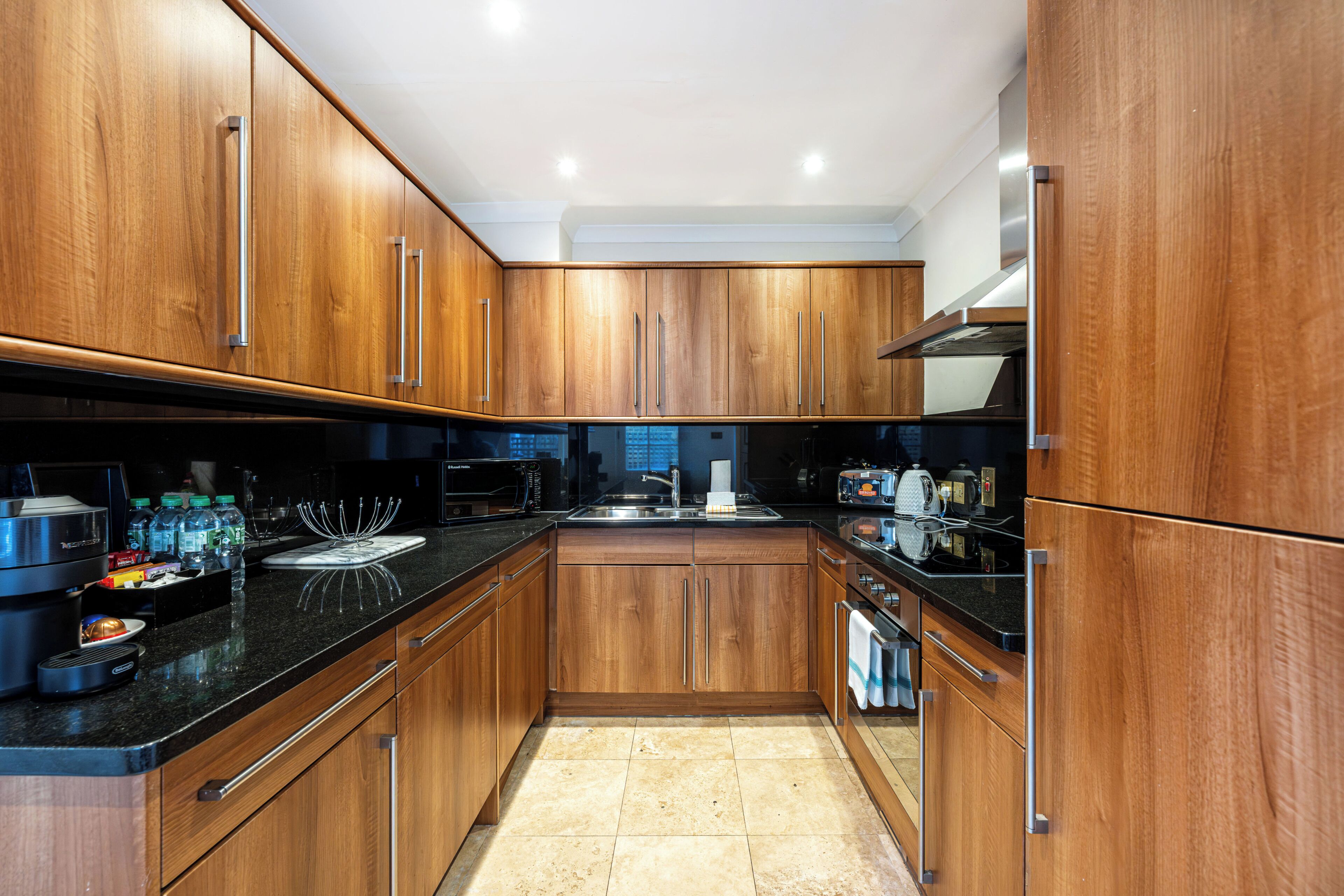 A modern kitchen with wooden cabinets, stainless steel appliances, and a black countertop.