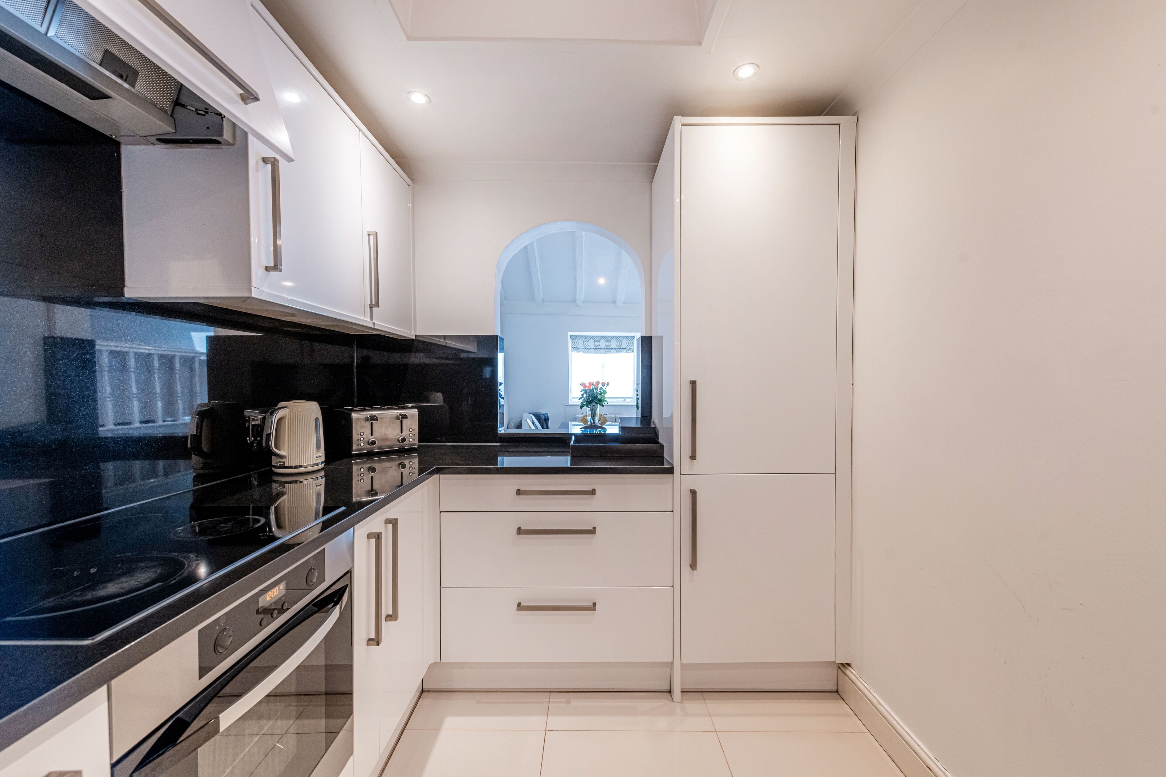 A modern kitchen with white cabinets, a black countertop, and a built-in oven.
