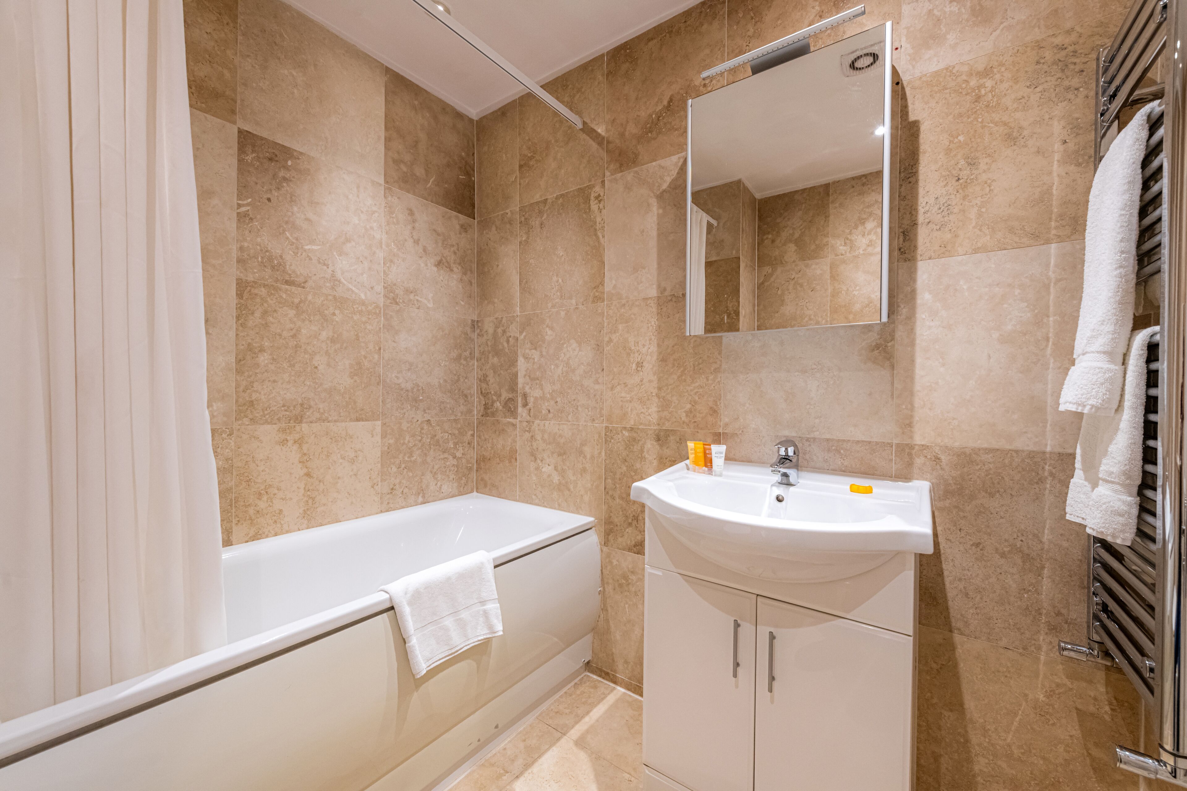 Een moderne badkamer met een bad, een wastafel en een spiegel.